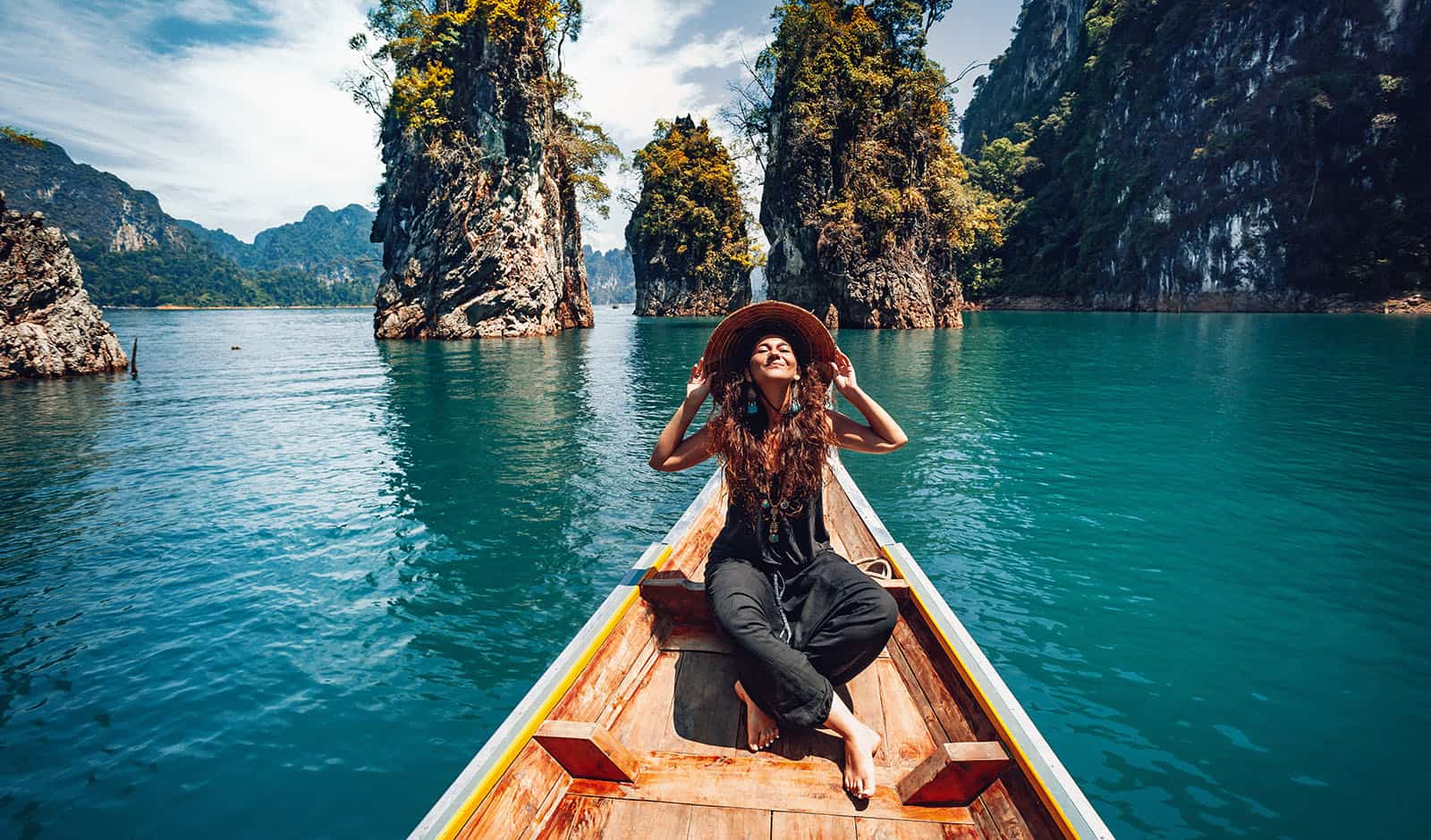 happy young woman tourist in asian hat on the boat at lake