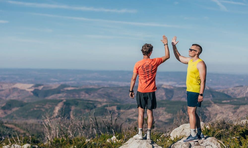 two-men-high-fiving-on-top-off-mountain-rockay