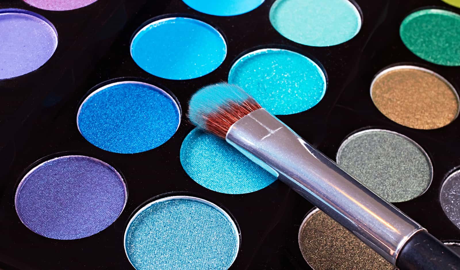 eyeshadow brush sitting on an eyeshadow paletted with blue shadow