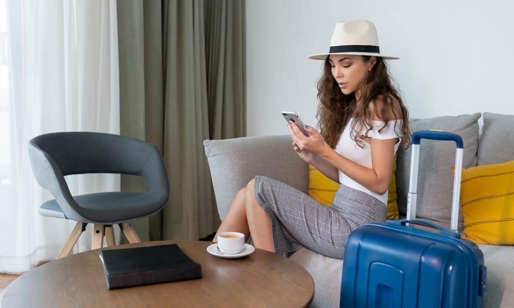 cute girl on phone while sitting on couch with luggage