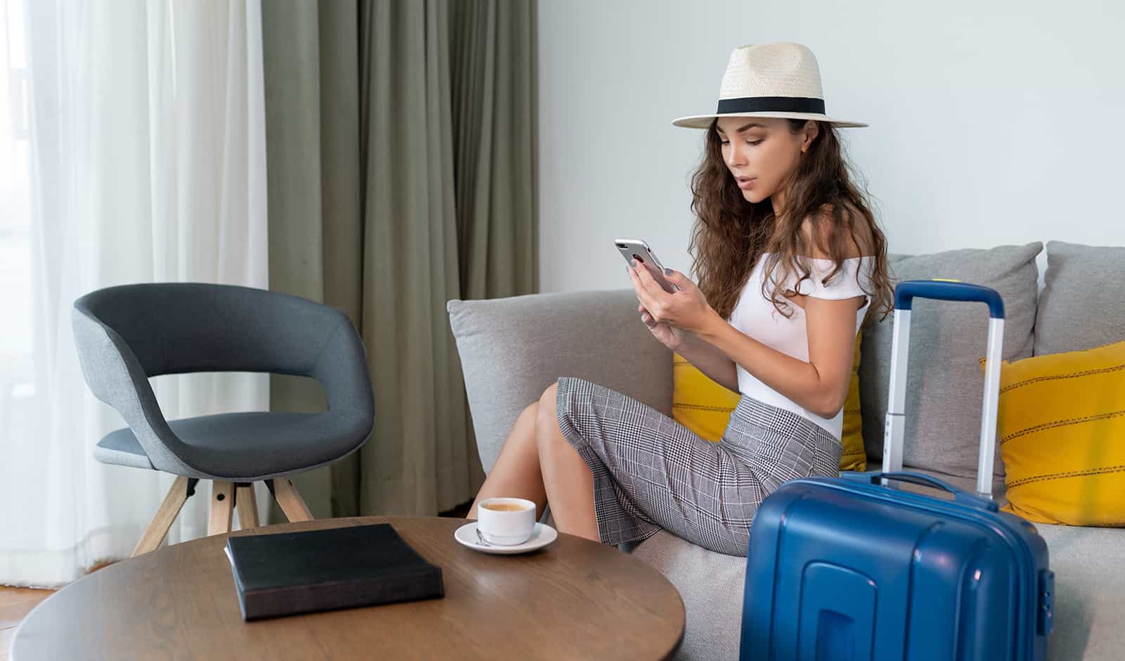 cute girl on phone while sitting on couch with luggage