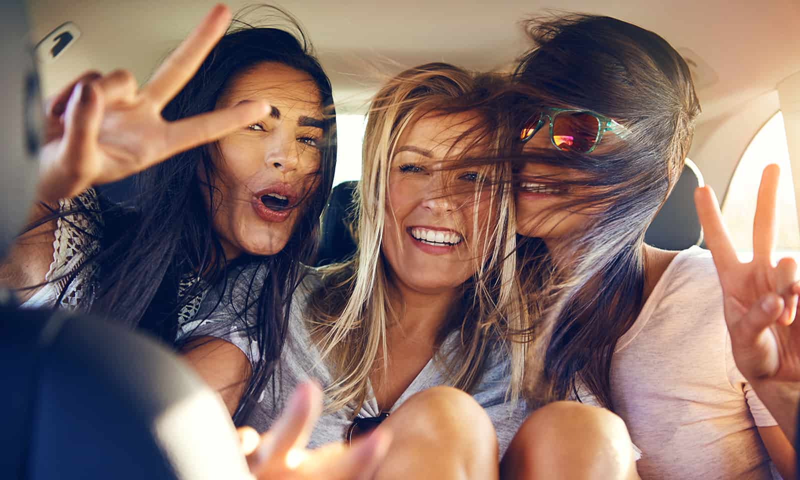 Three beautiful female friends make peace signs