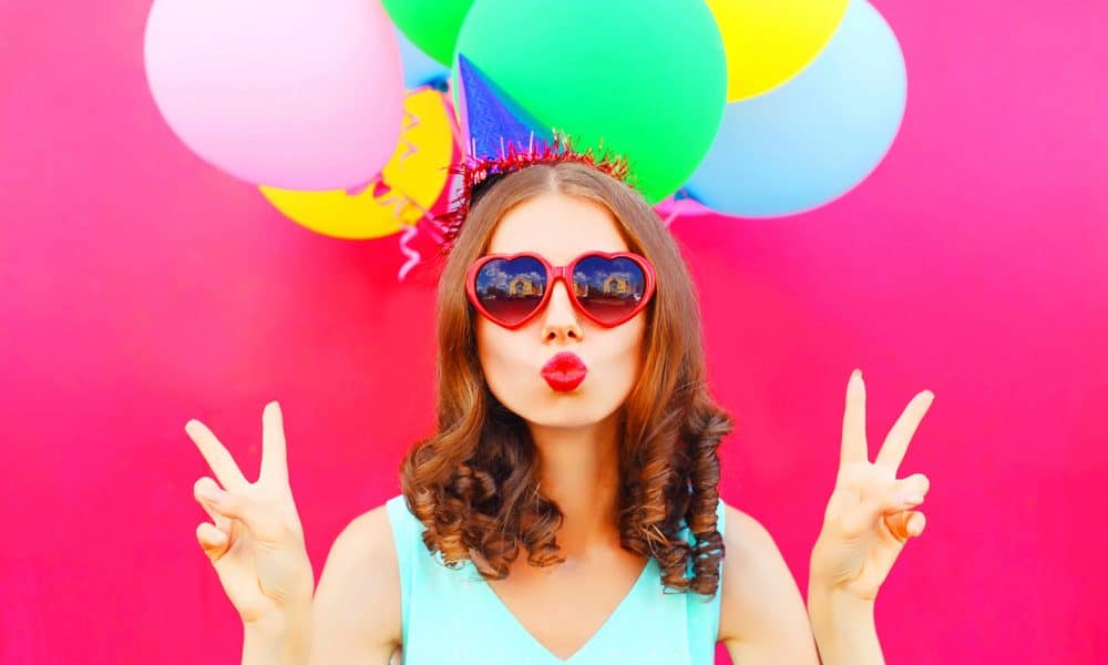 portrait woman in a birthday cap is blowing lips holds an air co