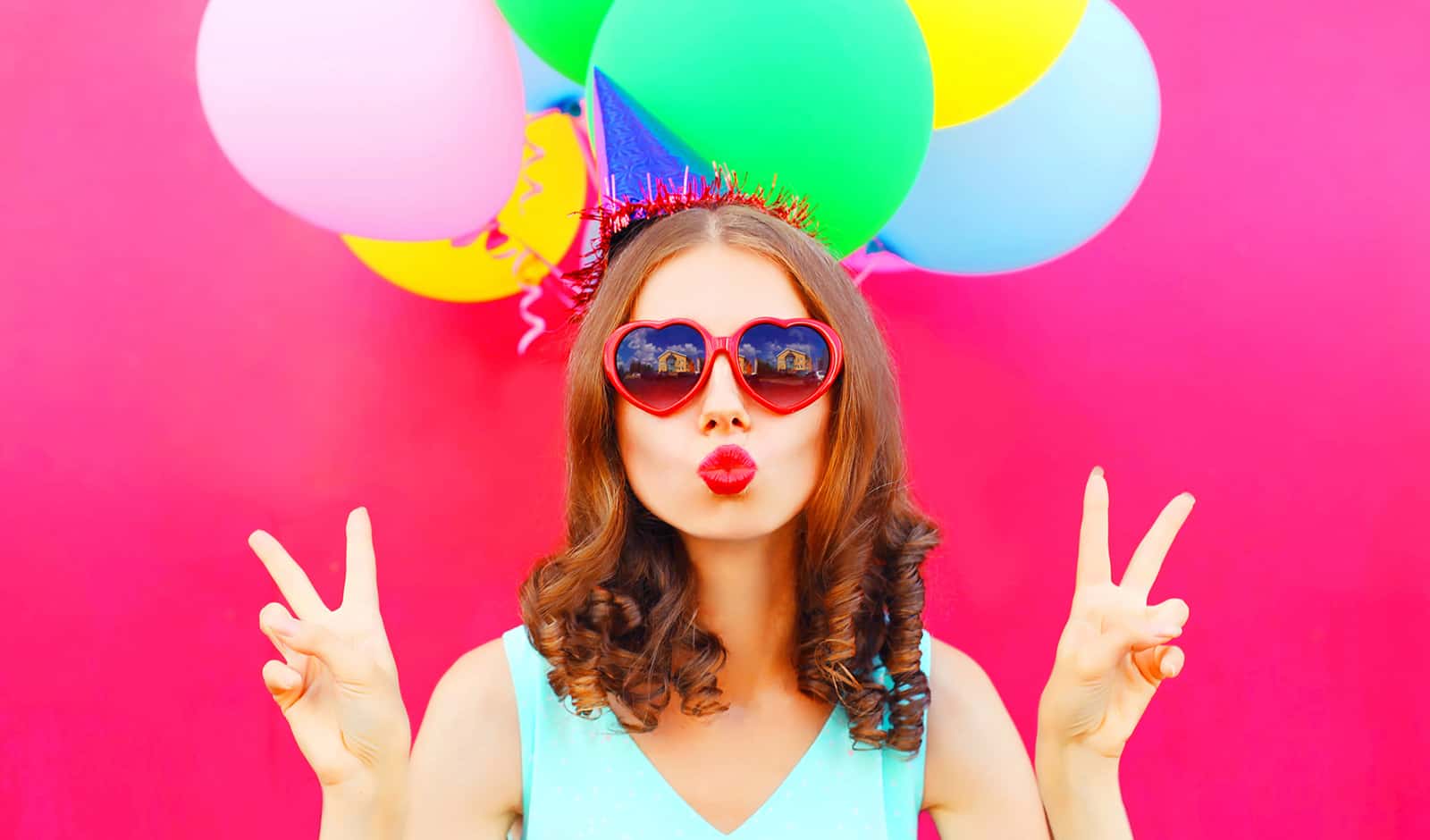 portrait woman in a birthday cap is blowing lips holds an air co