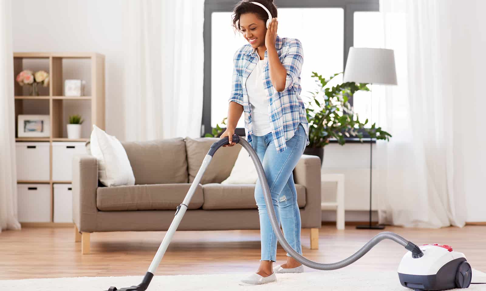 woman or housewife with vacuum cleaner at home